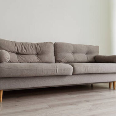 Grey sofa in monochromatic living room with green curtains