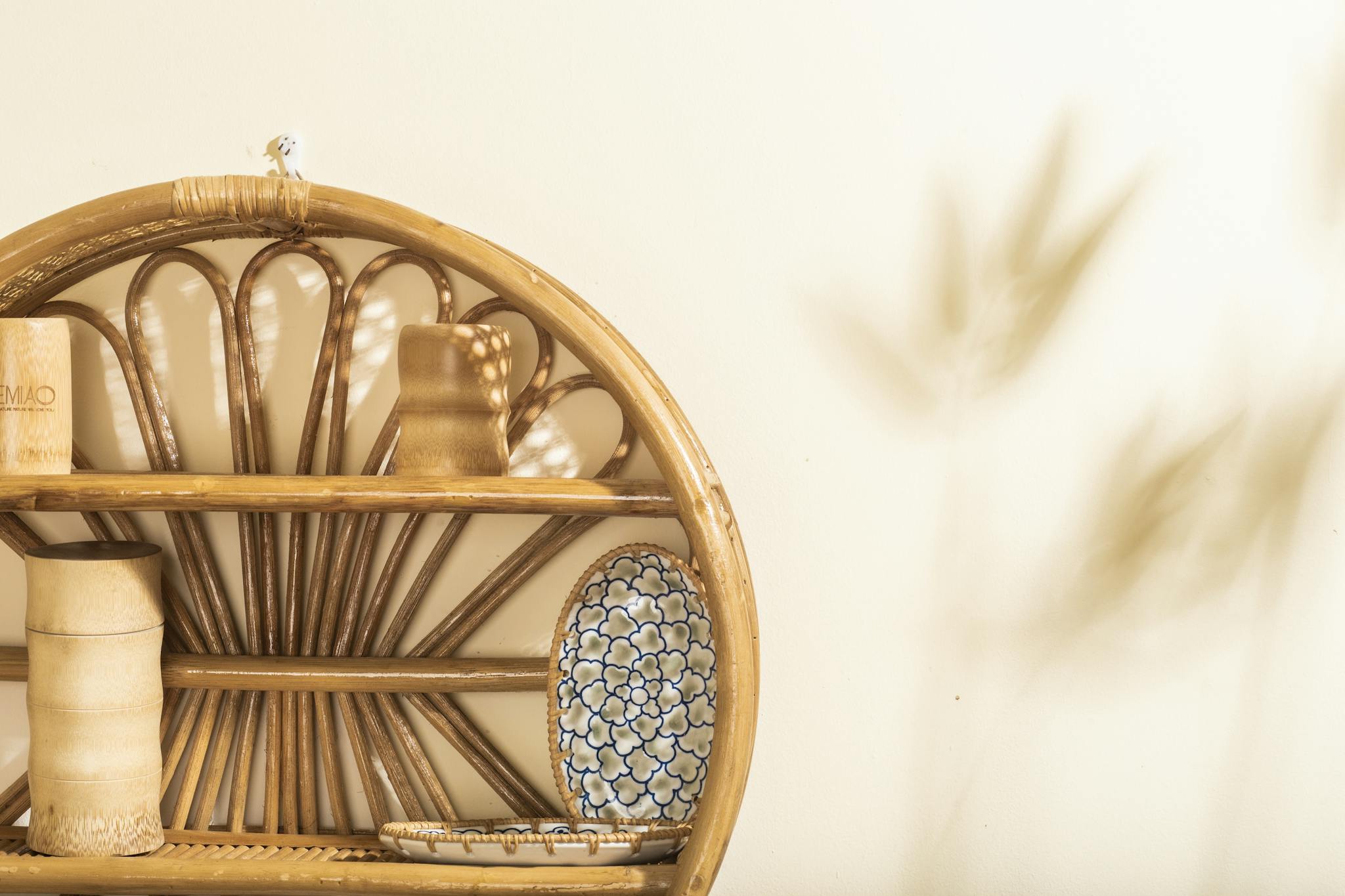 Elegant rattan wall shelf with ceramics in a bright, minimalist interior setting, perfect for modern decor.