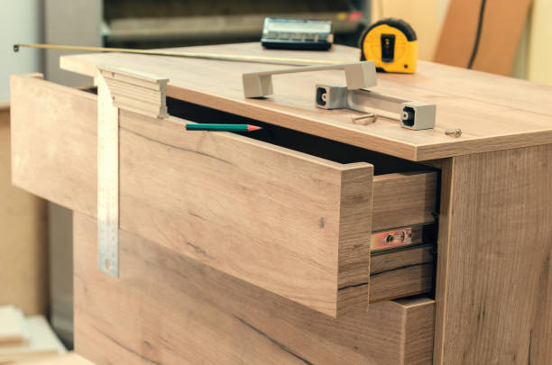 Assembling furniture from chipboard, using a cordless screwdriver, close up.