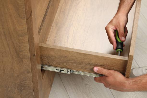 Man with screwdriver assembling drawer indoors, closeup
